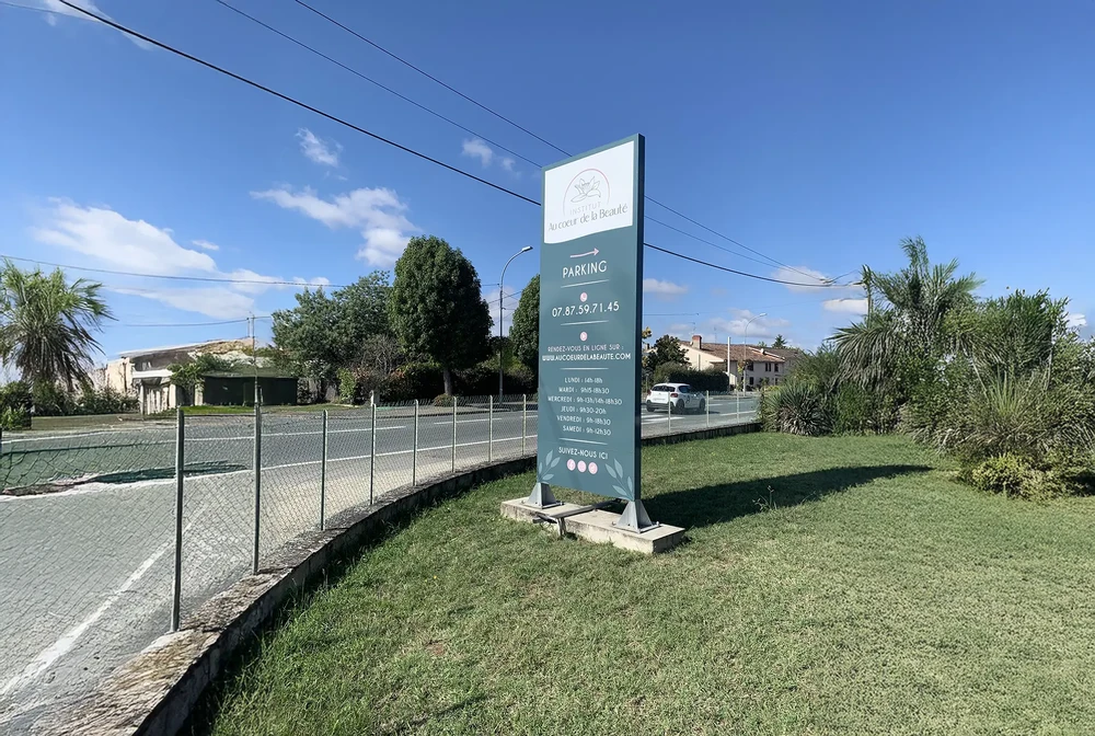 Parking extérieur avec panneau signalétique professionnel sur pelouse