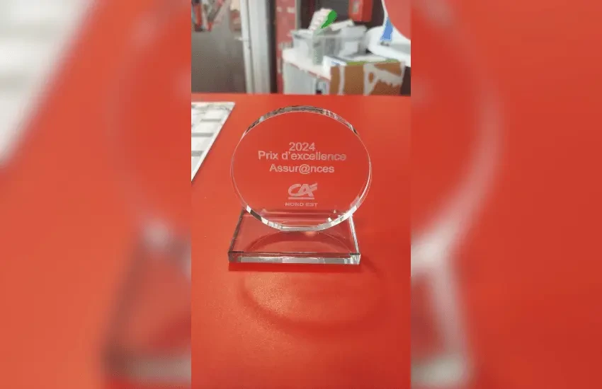 Ensemble d'objets promotionnels disposés sur surface en bois clair : t-shirt bleu marine avec motifs géométriques verts et blancs, horloge murale, casquette bicolore, étiquettes suspendues, sac shopping